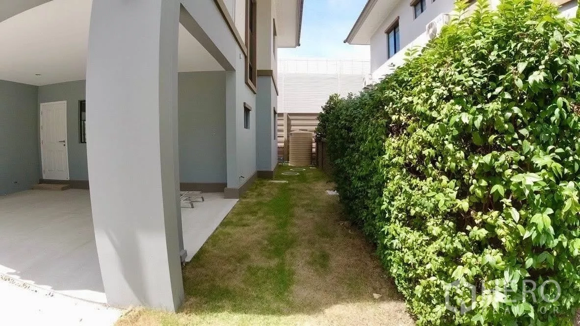 独立式住宅 出租或出售在Bang Phli, Samut Prakan - 带顶车位与侧院草坪，旁侧高大绿篱。