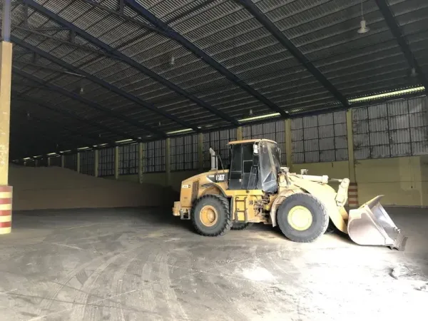 Warehouse for rent in Phra Nakhon Si Ayutthaya - High-clearance warehouse interior with a wheel loader parked on the concrete floor and ventilated side windows.