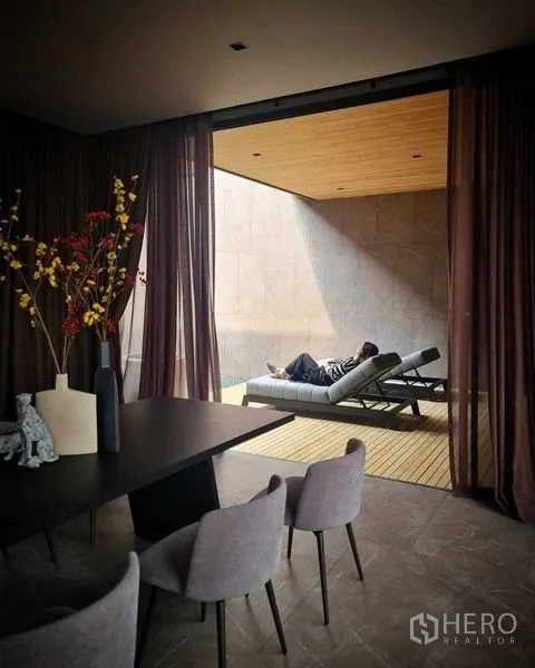 独立式住宅 出售在Lat Phrao, Bangkok - 室内休闲区开启至有顶露台与躺椅，帘幕轻拂。