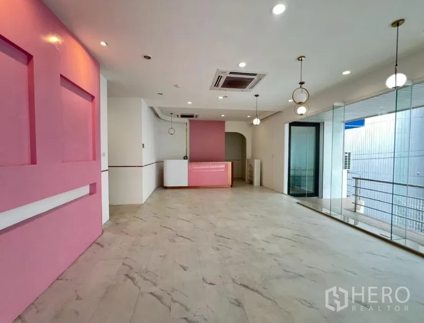 零售空间 出租在Watthana, Bangkok - 明亮商铺空间，仿大理石地面、粉色特色墙、玻璃立面与吊灯。