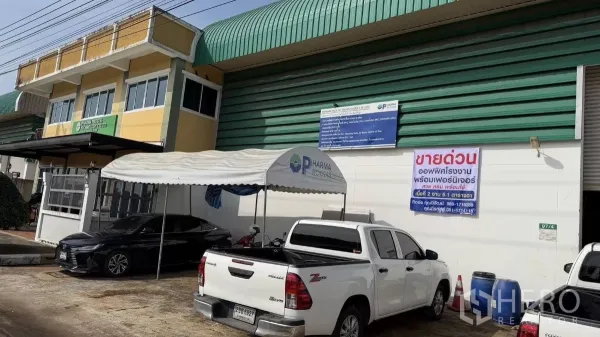 โรงงาน ขายในThanyaburi, Pathum Thani - โรงงานหน้าถนน หลังคาเมทัลชีทสีเขียว มีอาคารสำนักงานสีเหลือง กันสาด ที่จอดรถ และประตูม้วน