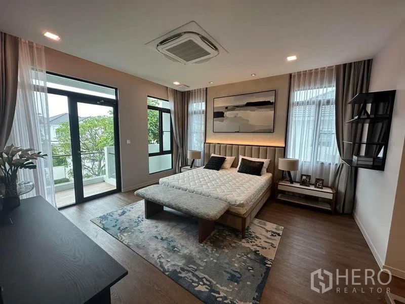 Detached House for rent in Samut Prakan - Master bedroom with balcony access and floor-to-ceiling windows.