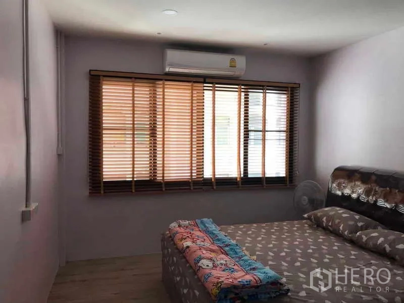 Townhouse for rent - Primary bedroom with large window, timber blinds, split air-conditioner and wood-style flooring.