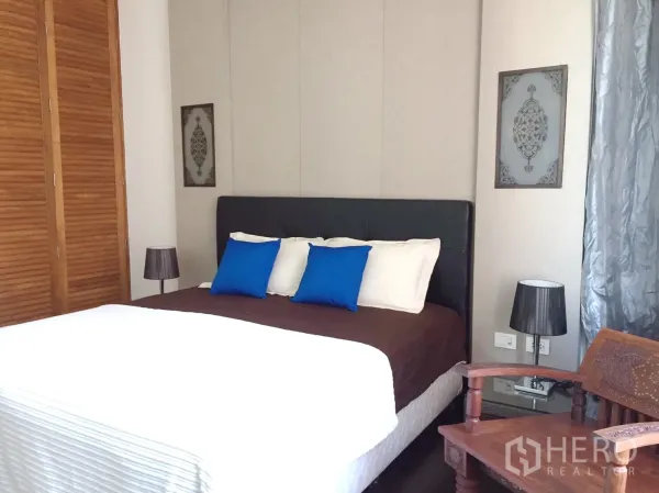 คอนโด ให้เช่าในKhlong Toei, Bangkok - ห้องนอนหลัก เตียงหัวบุ บานตู้เสื้อผ้าไม้ และโคมไฟข้างเตียง