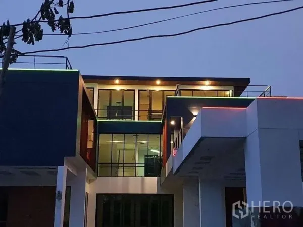 独立式住宅 出租在Phra Khanong, Bangkok - 夜景外立面，落地窗与暖色外墙灯。