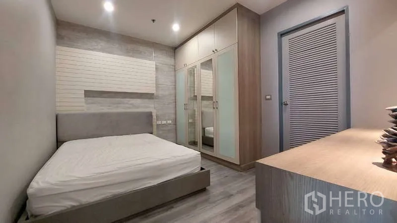 คอนโด ให้เช่าในWatthana, Bangkok - ห้องนอนพร้อมตู้เสื้อผ้าบิวท์อินบานกระจกและหัวเตียงสีเทาในคอนโดกรุงเทพฯ
