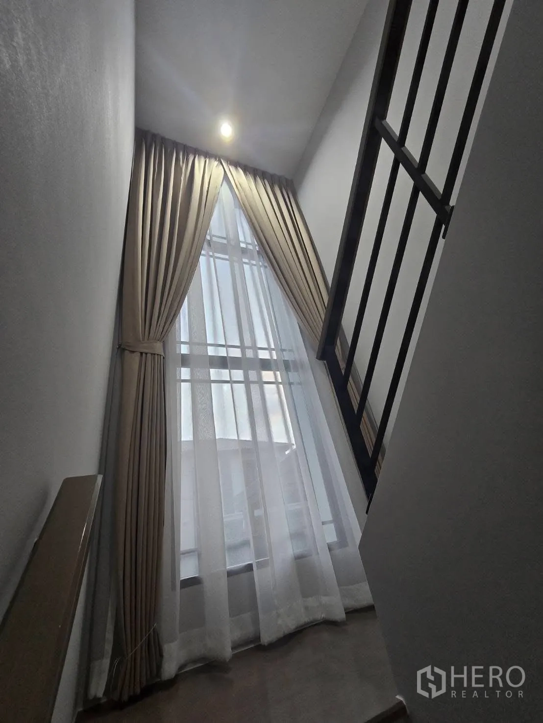 Semi-detached House for rent in Bang Phli, Samut Prakan - Staircase landing with tall window, sheer drapes, and metal railing.