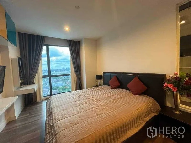 Condominium for sale - Bright bedroom with floor-to-ceiling window overlooking Bangkok city view.