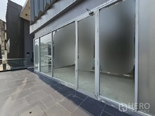 พื้นที่ขายปลีก ให้เช่า - ด้านหน้าพื้นที่ร้านค้า กระจกเต็มบาน พร้อมระเบียงทางเดินปูหินกว้าง