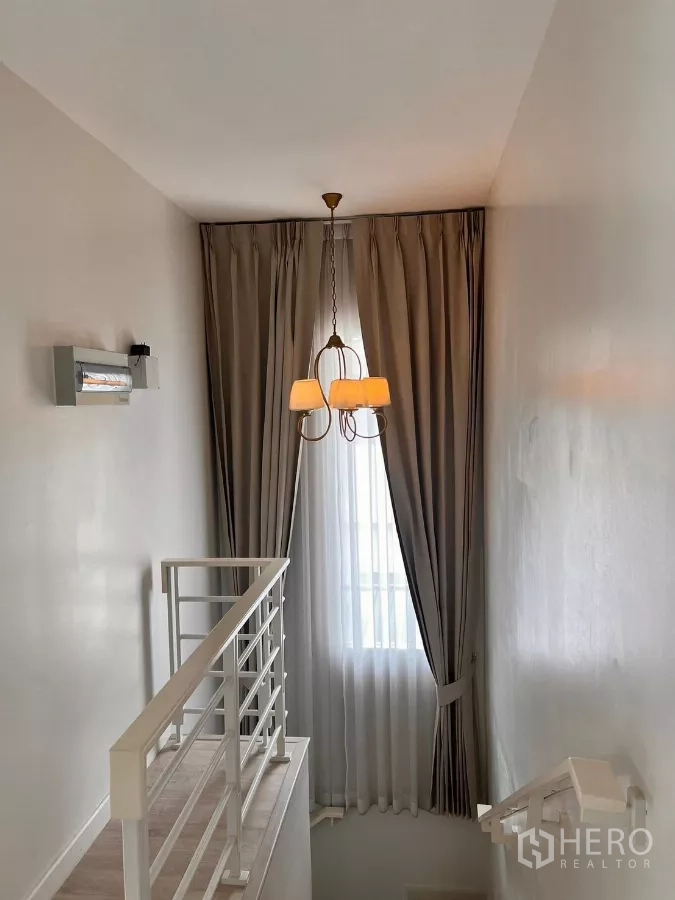 บ้าน ให้เช่าในLat Krabang, Bangkok - โถงบันไดชั้นบนพร้อมโคมไฟชานเดอเลียร์และผ้าม่านสูง