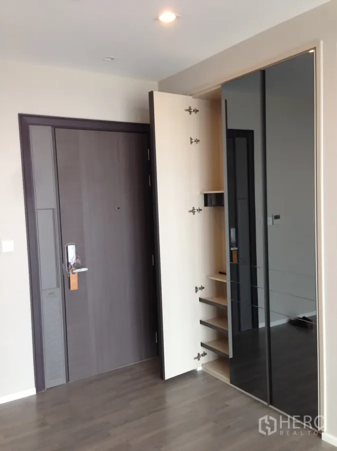 Condominium for rent in Bang Sue, Bangkok - Condo entry with dark wood door, built-in shoe cabinet and mirrored wardrobe.