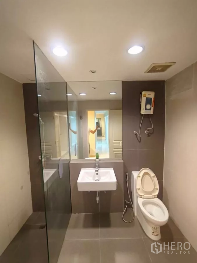 公寓 出租在Khlong Toei, Bangkok - 现代卫生间，带玻璃淋浴间、壁挂式洗手盆和马桶。