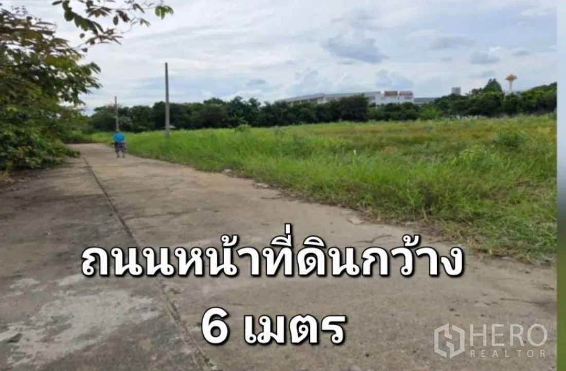 Land for sale in Khlong Luang, Pathum Thani - Concrete access road beside open grassy land with utility poles.