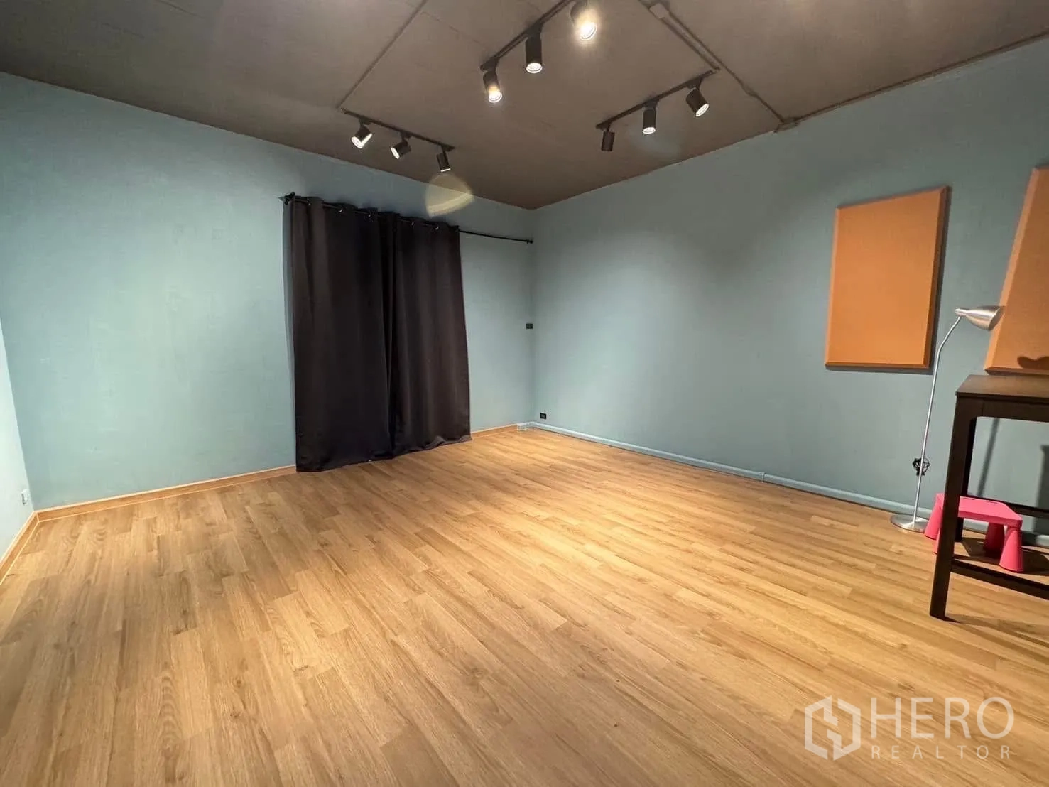 家庭办公室 for rent in Watthana, Bangkok - 宽敞的工作室式房间，木地板、蓝色墙面与轨道灯。