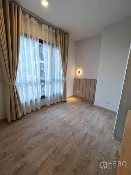 คอนโด ให้เช่า - ห้องนอนสว่าง หน้าต่างสูงเต็มบาน ม่านโปร่ง และพื้นไม้โทนอุ่น