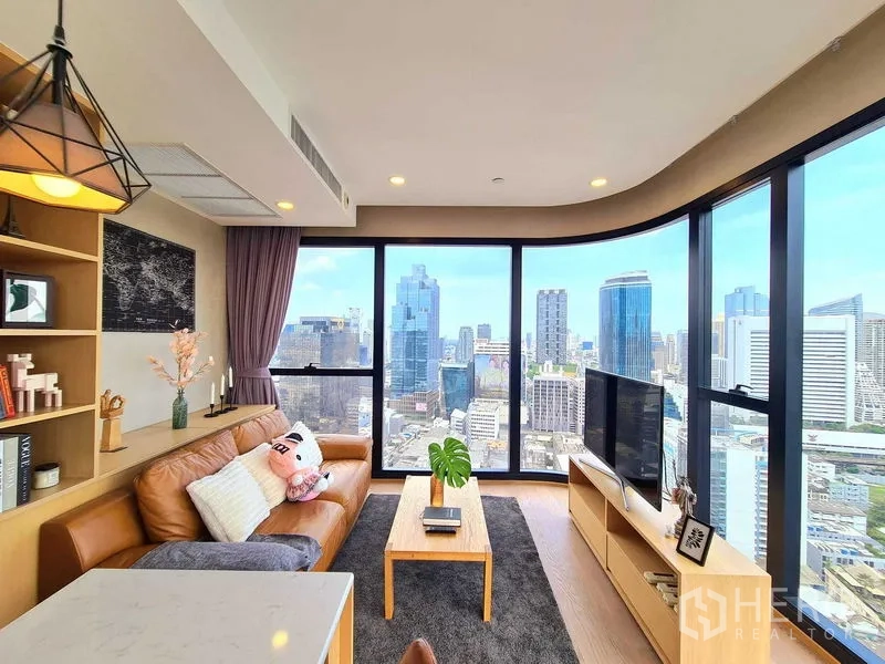Condominium for rent in Bang Rak, Bangkok - Panoramic living space with TV stand and wraparound floor-to-ceiling windows.