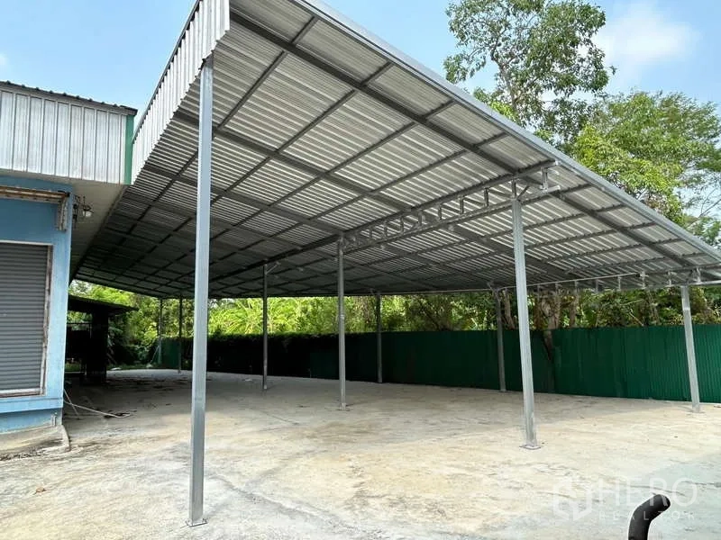 Warehouse for rent in Sam Phran, Nakhon Pathom - Large covered loading bay with high metal roof and spacious yard.