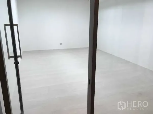 Office Space for rent in Pak Kret, Nonthaburi - Bright empty office room with light wood flooring viewed through a glass door.