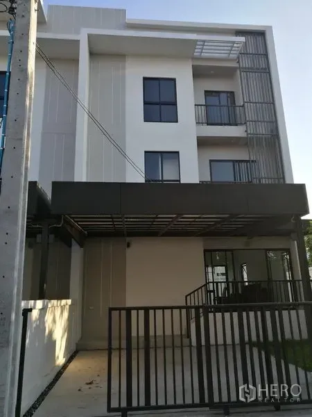 Townhouse for rent in Saphan Sung, Bangkok - Three-storey modern townhouse facade with gated carport and balconies.