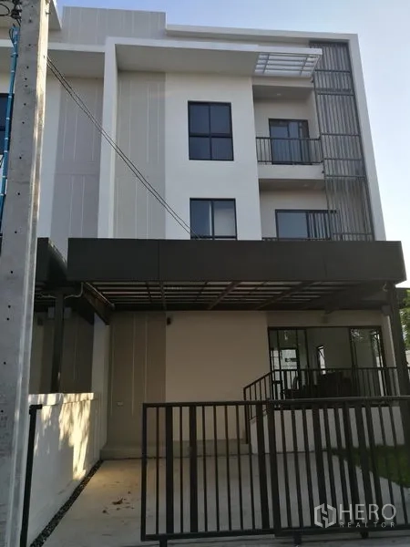Townhouse for rent in Saphan Sung, Bangkok - Three-storey modern townhouse facade with gated carport and balconies.