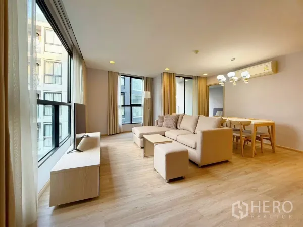 คอนโด ให้เช่าหรือขายในWatthana, Bangkok - ห้องนั่งเล่นมุมอาคาร กระจกเต็มบาน โซฟาสีเบจ และชั้นวางทีวี