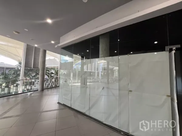 零售空间 出租 - 转角玻璃店面朝向中庭步道，可见顶棚与棕榈树景观。