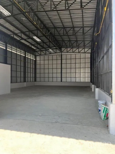 Warehouse for rent in Nonthaburi - Spacious warehouse interior with high steel trusses, concrete flooring and ample lighting.