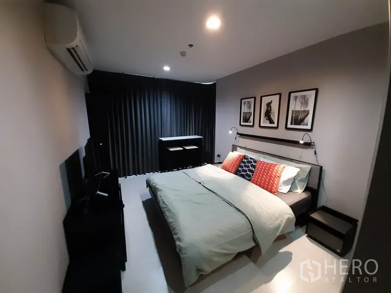 คอนโด ให้เช่าหรือขายในKhlong Toei, Bangkok - ห้องนอนใหญ่เตียงคิง ไฟอ่านหนังสือติดผนัง ผ้าม่านสีเข้ม และกรอบรูปตกแต่งเหนือหัวเตียง