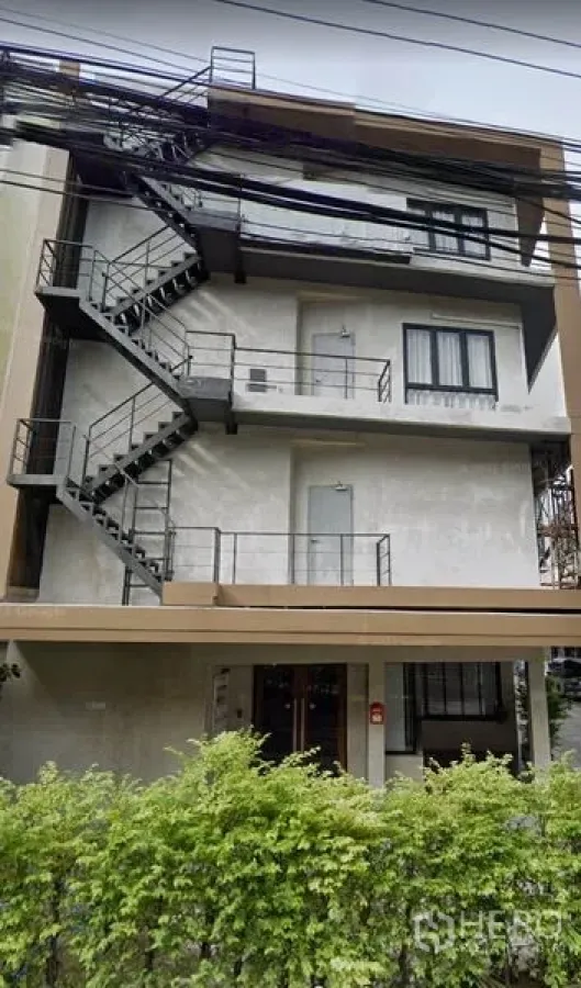 สำนักงาน ให้เช่าในPhra Khanong, Bangkok - อาคารสำนักงาน 4 ชั้นพร้อมบันไดหนีไฟภายนอกและพุ่มไม้ด้านหน้า ย่านพระโขนง