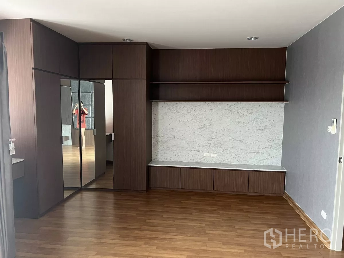 Detached House for rent or sale in Don Mueang, Bangkok - Bedroom with built‑in wardrobes, mirrored doors and marble‑look TV wall and cabinets.