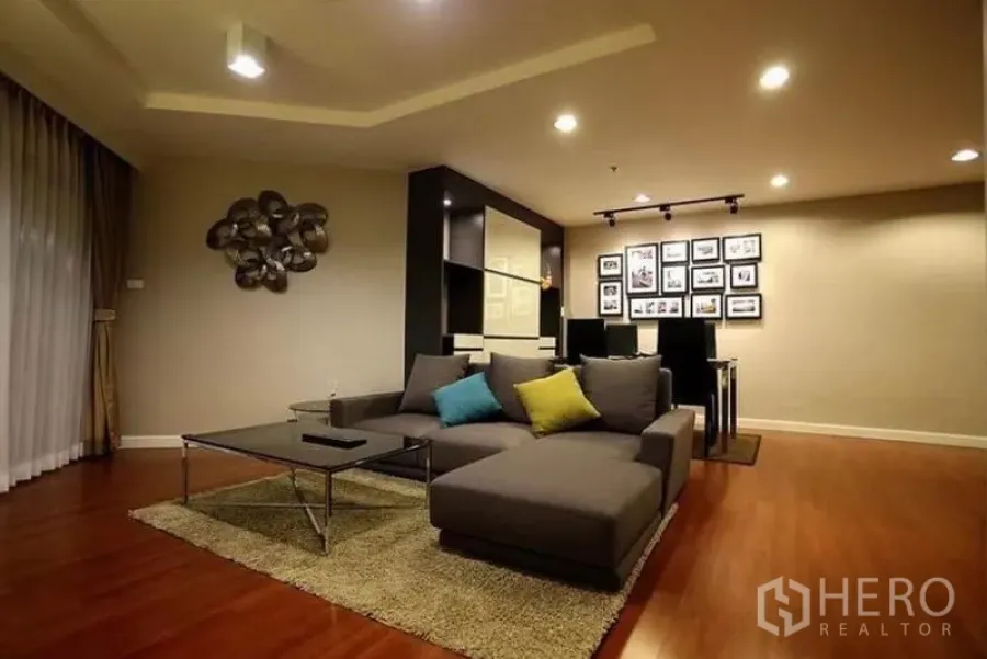 Condominium for rent in Huai Khwang, Bangkok - Warm living room of a 2-bedroom Huai Khwang condo with L-shaped sofa, coffee table and wood floors.