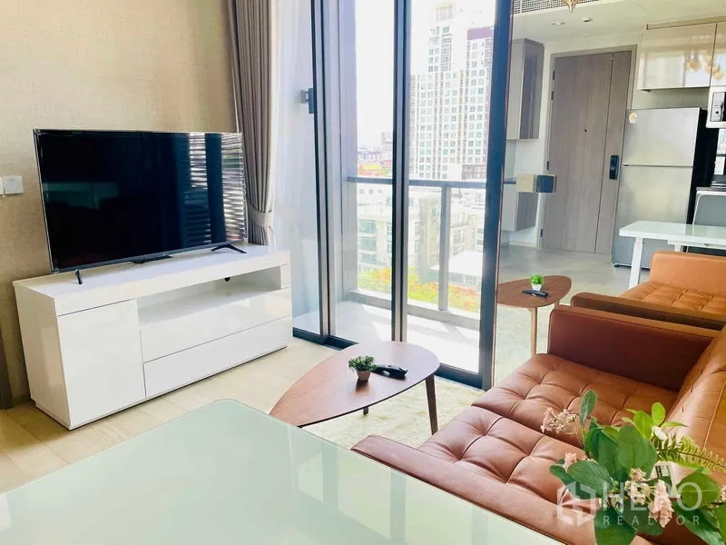 公寓 出租在Ratchathewi, Bangkok - 面向阳台的起居区，电视柜、玻璃门与现代沙发。