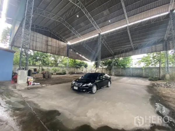 Warehouse for rent in Suan Luang, Bangkok - Open-air warehouse bay with metal roof and large maneuvering area for trucks.