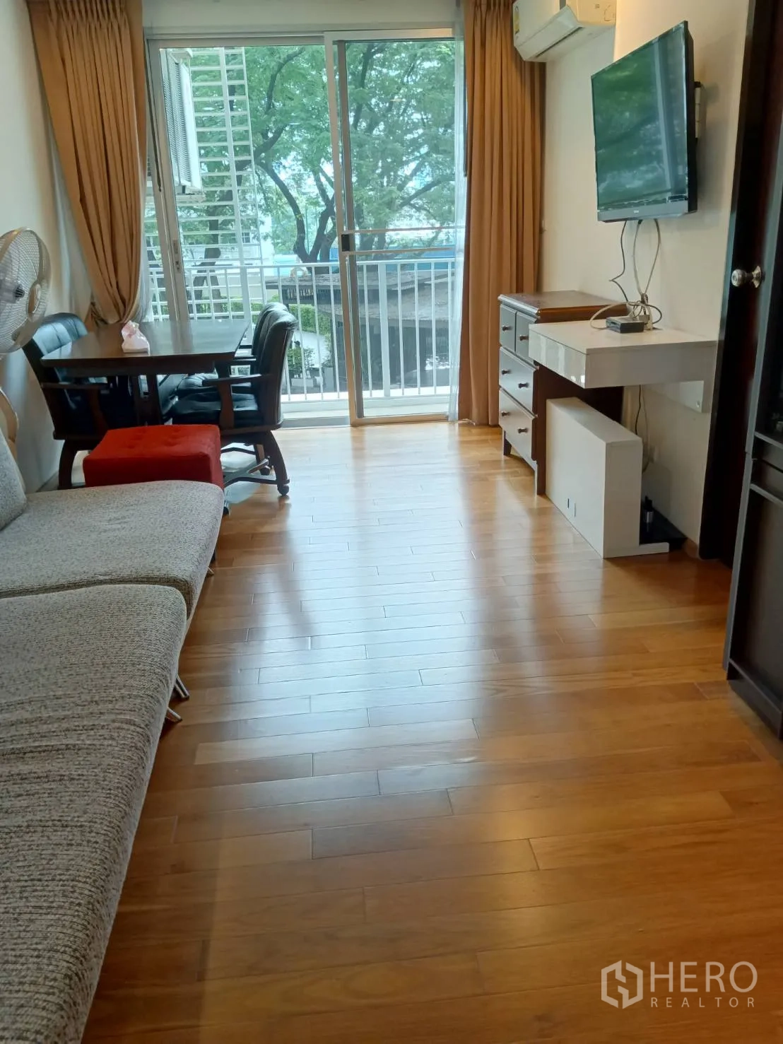 Condominium for sale in Chatuchak, Bangkok - Open-plan living area with TV wall, dining table and balcony access.