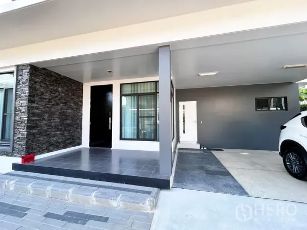 Detached House for rent or sale in Prawet, Bangkok - Covered carport and main entrance with stone accent wall.