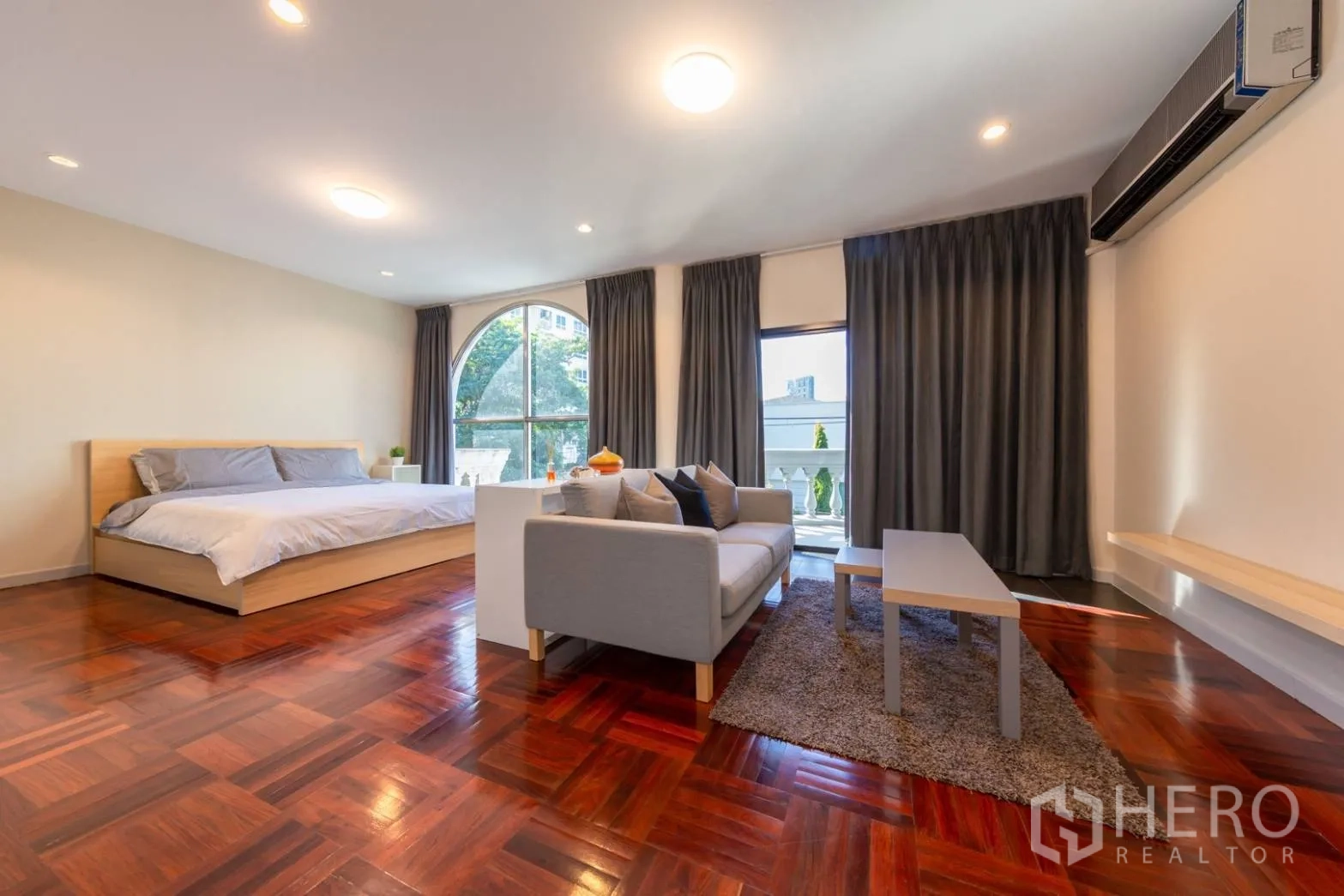带办公室的家 出租在Bang Rak, Bangkok - 主卧视角，可见休息区与通往阳台的落地玻璃门。