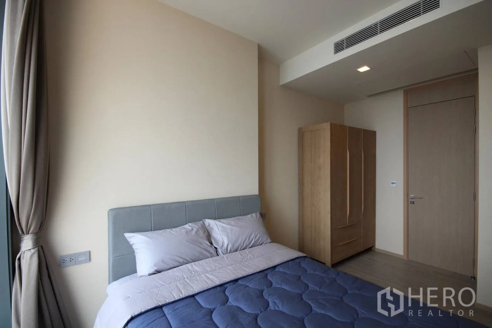 Condominium for rent in Watthana, Bangkok - Cozy second bedroom with large window, freestanding wardrobe, and neutral décor.