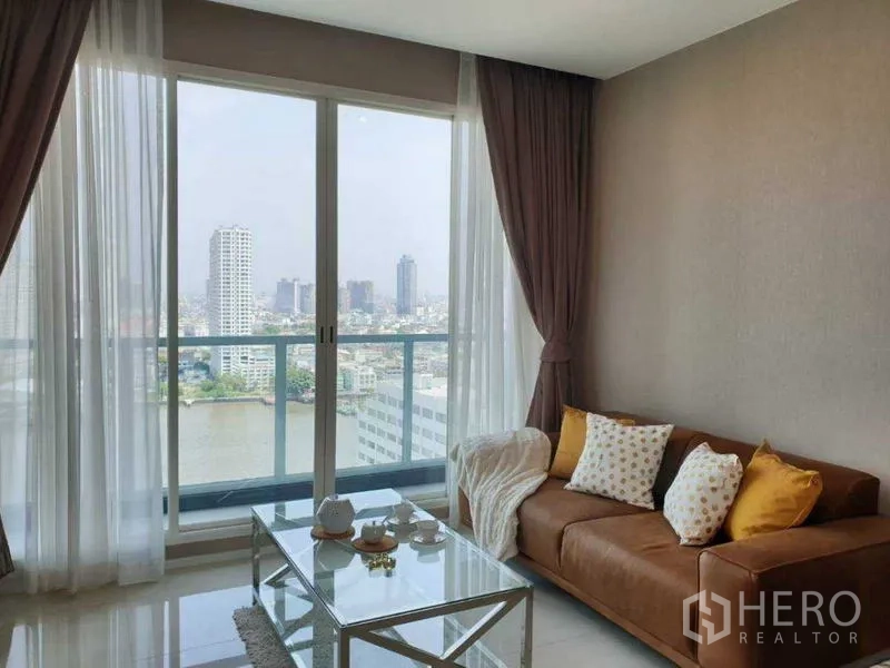 Condominium for rent in Bang Kho Laem, Bangkok - Living area with sofa and glass coffee table facing a river panorama.
