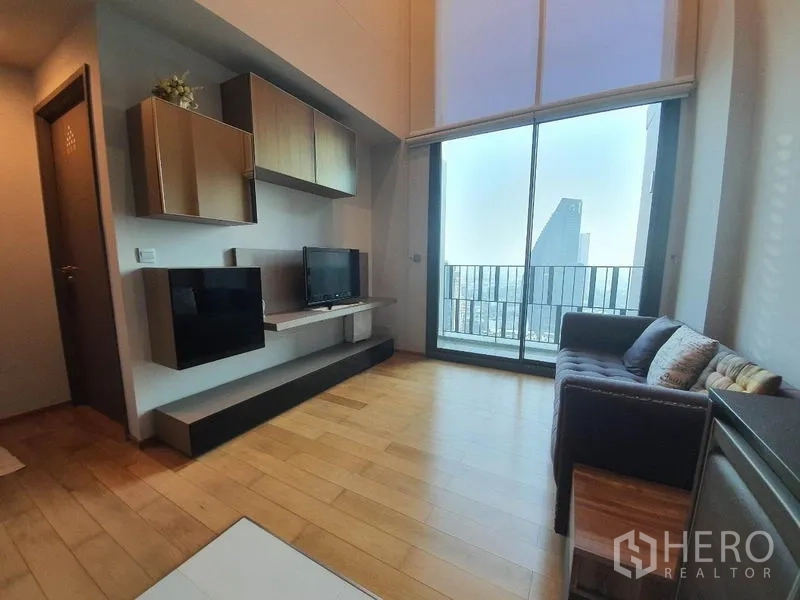 คอนโด ให้เช่าหรือขายในKhlong Toei, Bangkok - ห้องนั่งเล่นหน้าต่างสูงจรดเพดาน ผนังทีวีบิลท์อิน และประตูสไลด์สู่ระเบียง