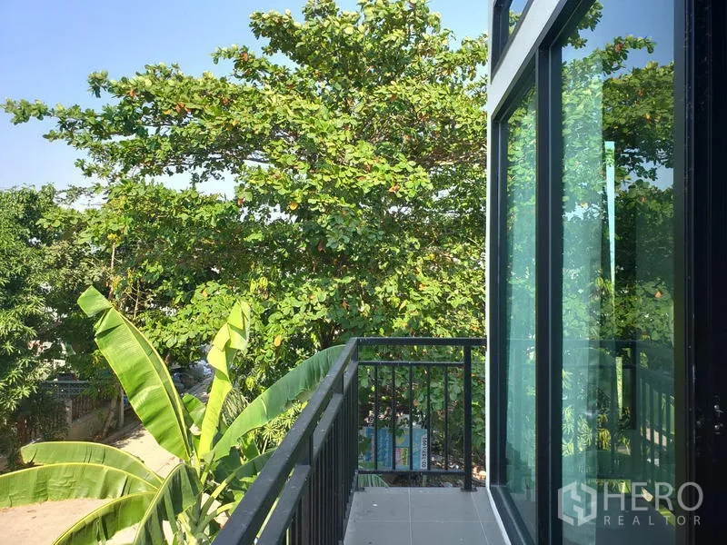 โรงงาน ให้เช่าหรือขายในLam Luk Ka, Pathum Thani - ระเบียงขนาดกะทัดรัด ราวเหล็กสีดำ ประตูกระจกบานเลื่อน มองเห็นต้นไม้เขียว