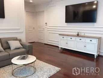 คอนโด ขายในWatthana, Bangkok - ห้องนั่งเล่นอบอุ่น โซฟาสีเทา พรม ทีวีติดผนัง และผนังบัวตกแต่ง