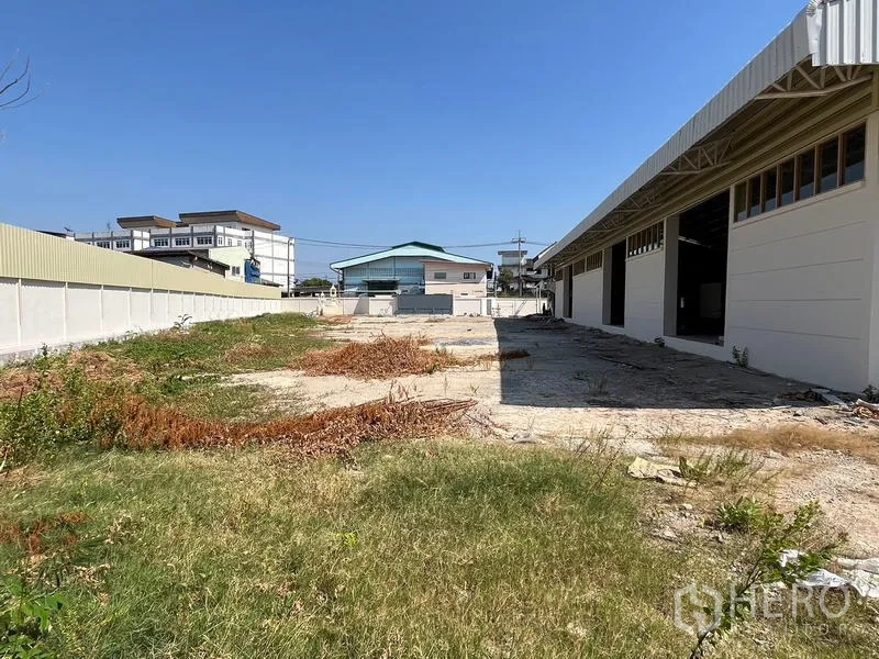 Warehouse for rent or sale - Large open yard facing warehouse bays suitable for parking or loading.