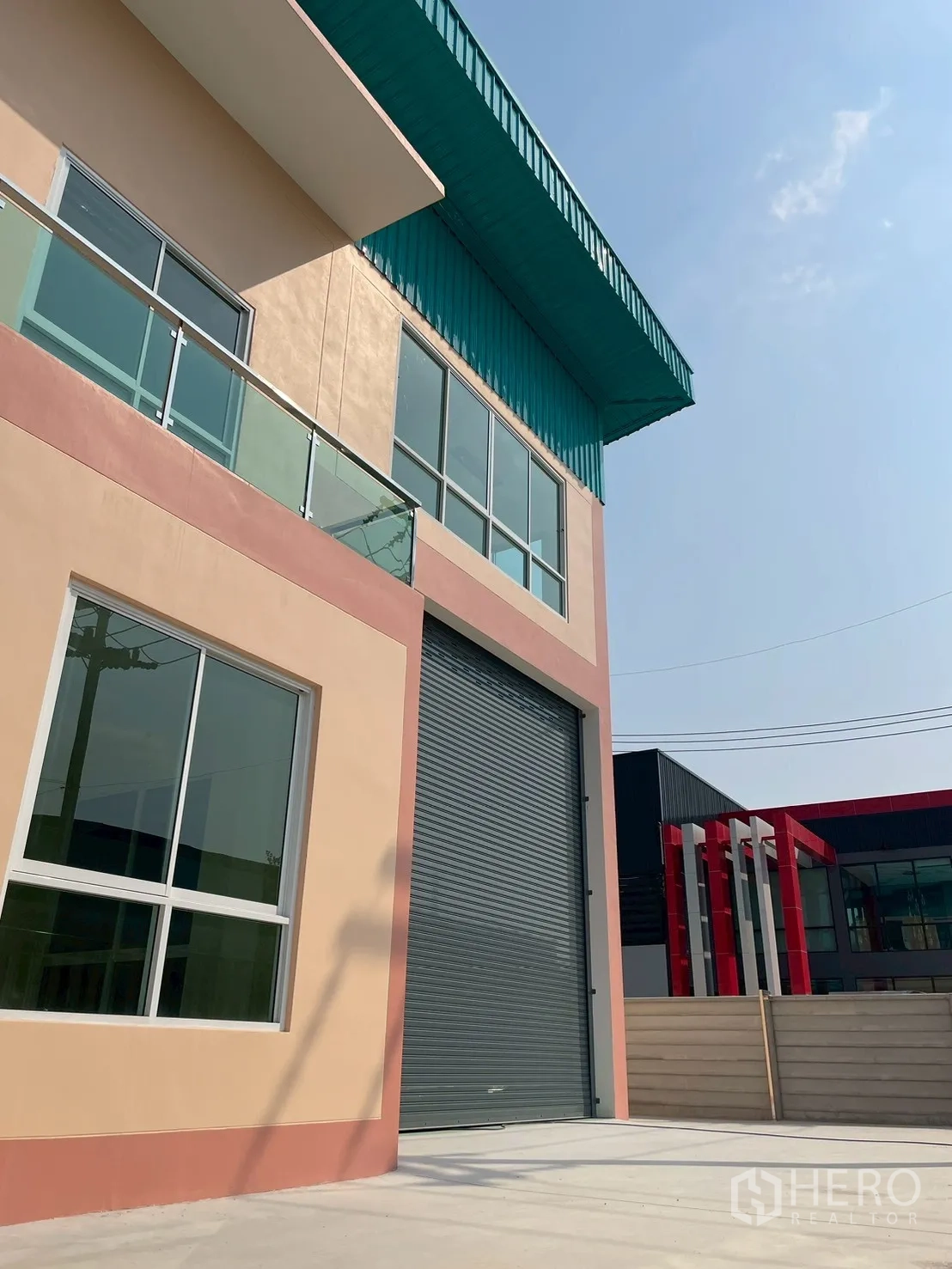 โรงงาน for sale in Sam Phran, Nakhon Pathom - ด้านหน้าโรงงานสมัยใหม่ หลังคาสีเขียว และประตูม้วนไฟฟ้าขนาดใหญ่