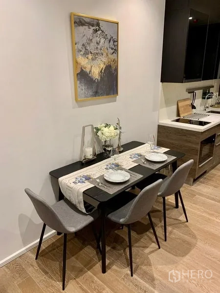 Condominium for rent in Pathum Wan, Bangkok - Dining nook set for four beside a compact kitchen with wood cabinets.