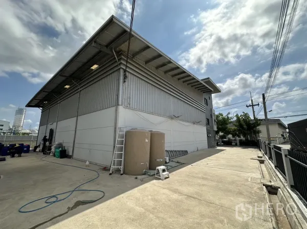 工厂 出租或出售在Pathum Thani - 钢板外墙仓库侧视图，宽阔混凝土场地便于装卸。
