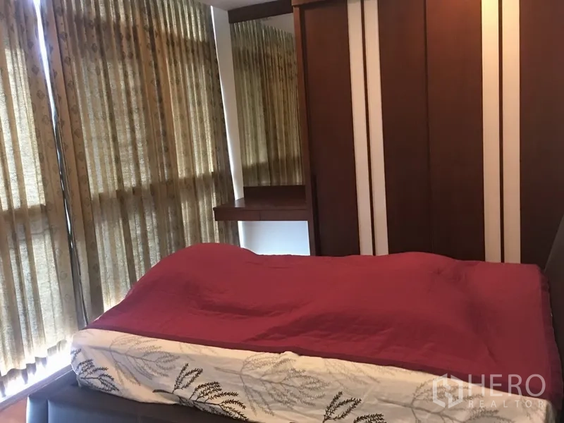 公寓 出租在Khlong Toei, Bangkok - 卧室带大窗与棕色窗帘，内置衣柜，床铺搭配酒红色被褥。