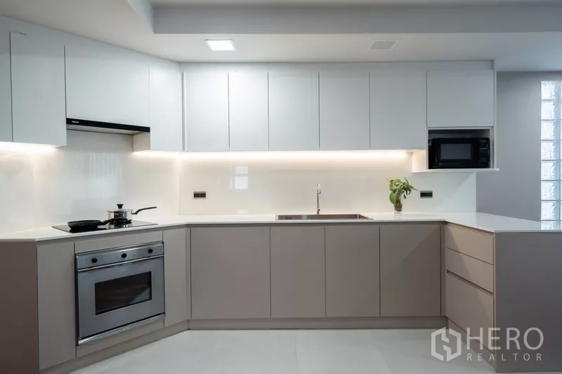 Apartment for rent - Modern L-shaped kitchen with built-in oven, microwave and ample cabinets.