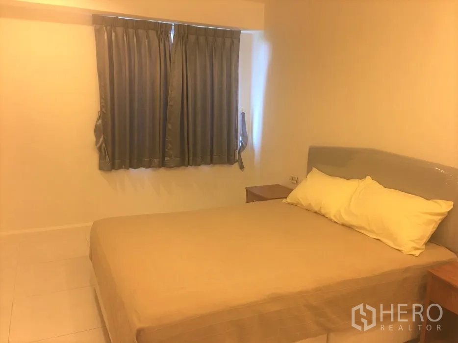 Condominium for rent in Watthana, Bangkok - Guest bedroom with beige bedding, side tables, and a curtained window.