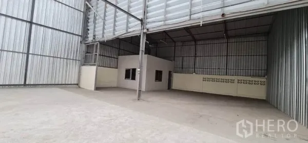 Warehouse for rent in Pak Kret, Nonthaburi - Spacious warehouse interior with high ceiling, concrete floor, and built-in office room.