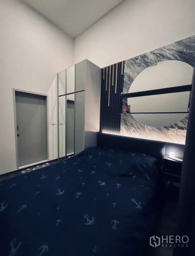 Condominium for rent in Chatuchak, Bangkok - Bedroom angle showing wardrobe and feature wall with circular mirror shelf.